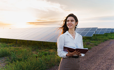 A woman stood with a notebook in front of rows of solar panels