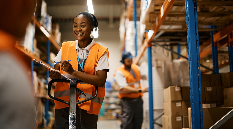 A worker in a warehouse writing on her clip board