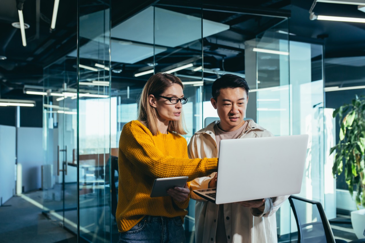 Two office workers sharing ideas with a laptop