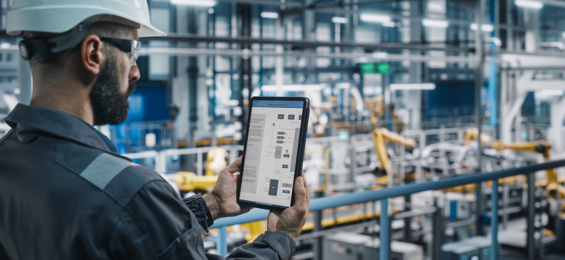 Hard hat employee reviewing systems on his tablet