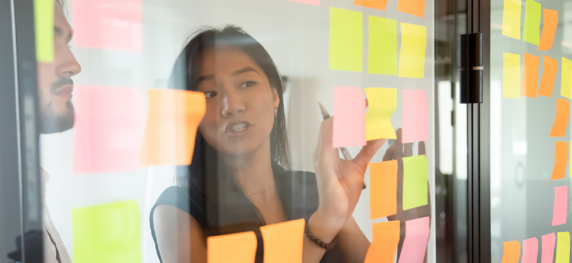 A worker adding a note to a transparent notice board