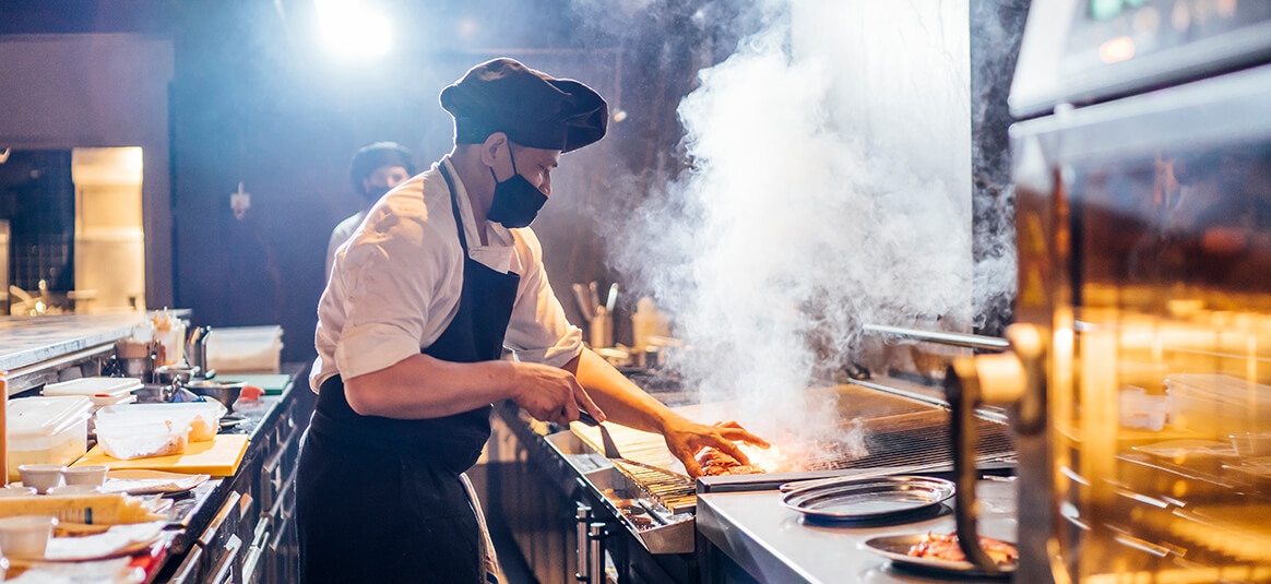 Chef cooking on a hot grill in a commercial kitchen