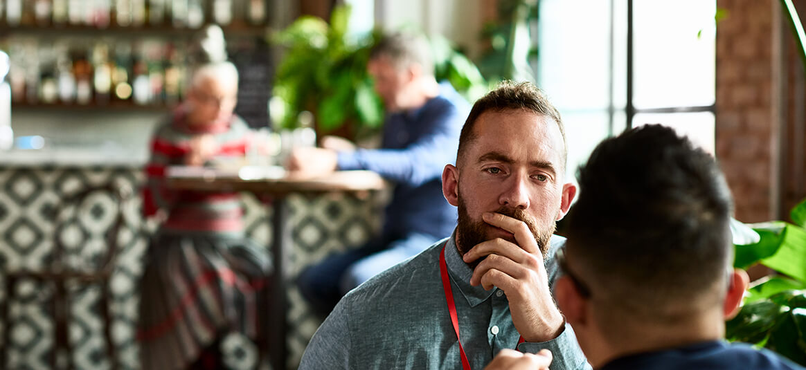 Two men seated in a cafe facing each other