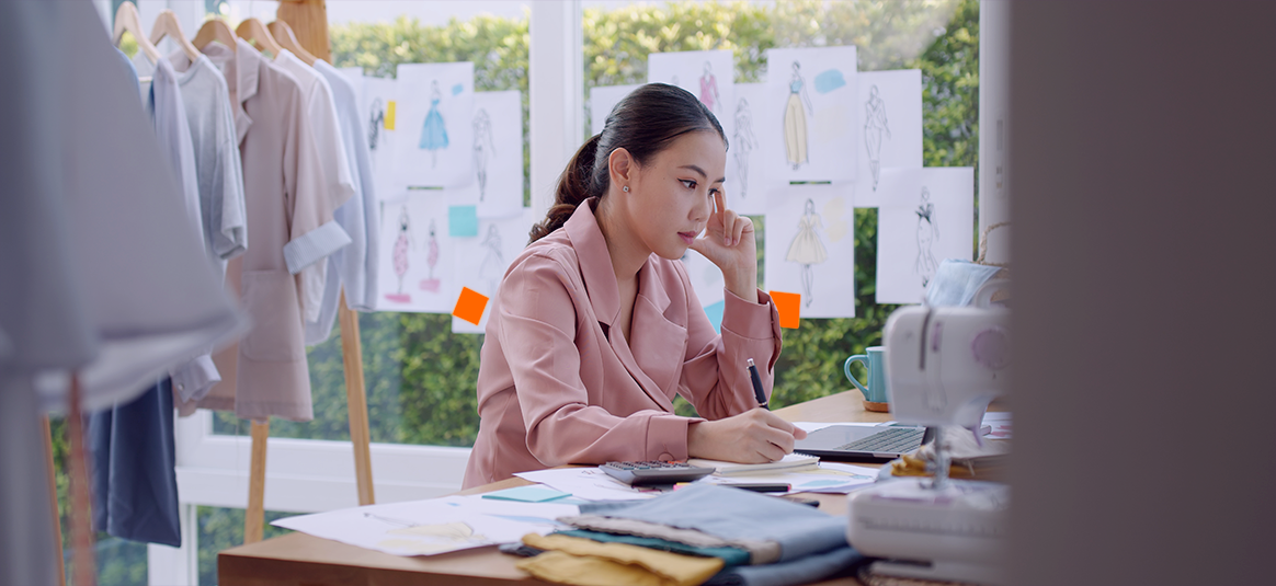 Photo of a woman concentrating on a calculator and open laptop.