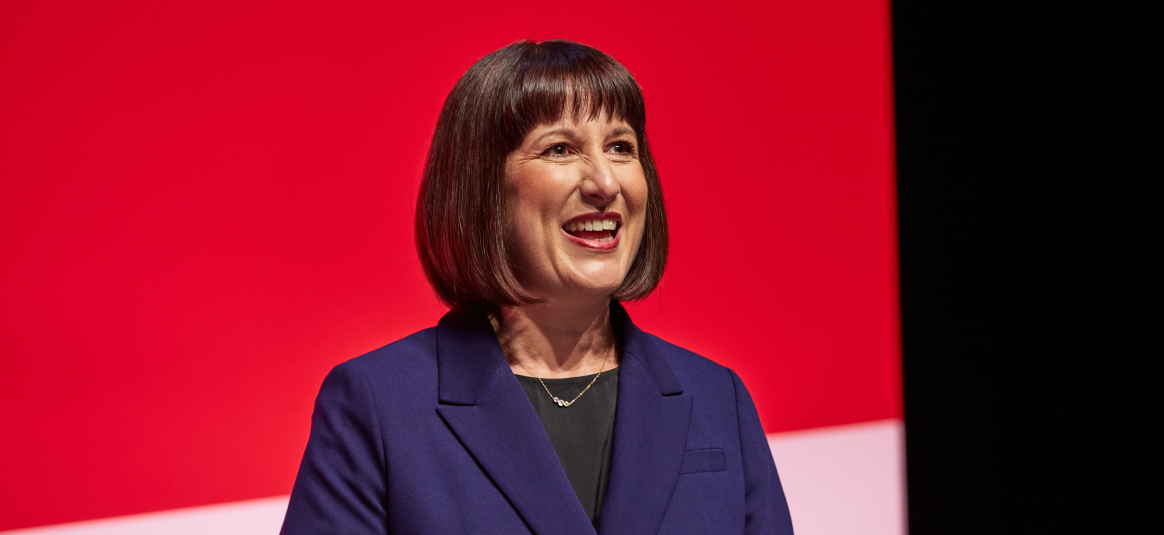 Chancellor Rachel Reeves, smiling against a red backdrop