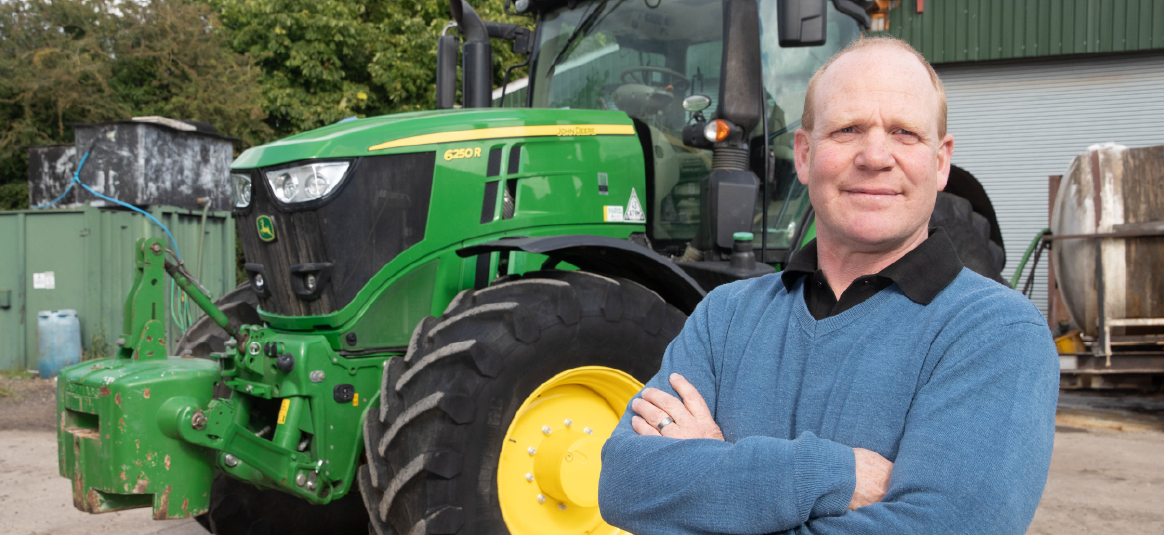 Photo of a farmer and his green tractor on a farm