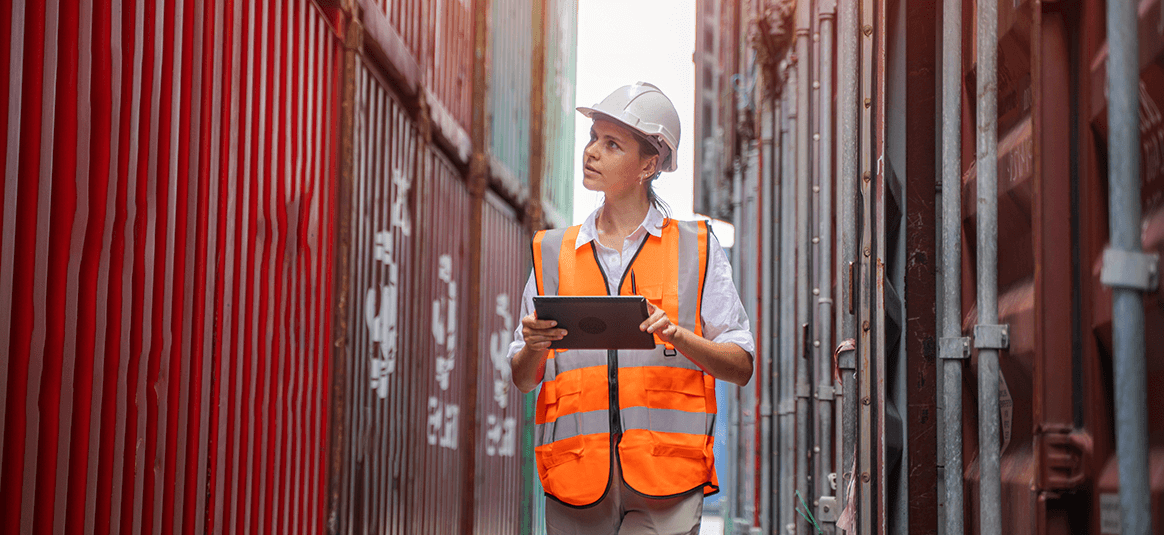 Woman with clipboard reviewing shipping containers