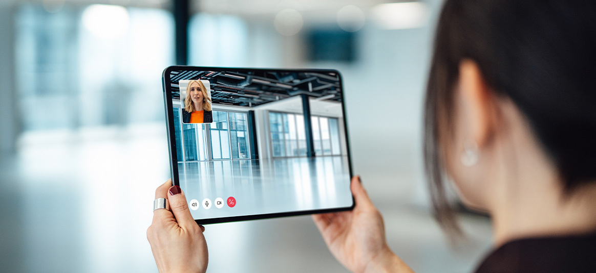 woman displaying an empty office space to a colleague, via Zoom call on iPad