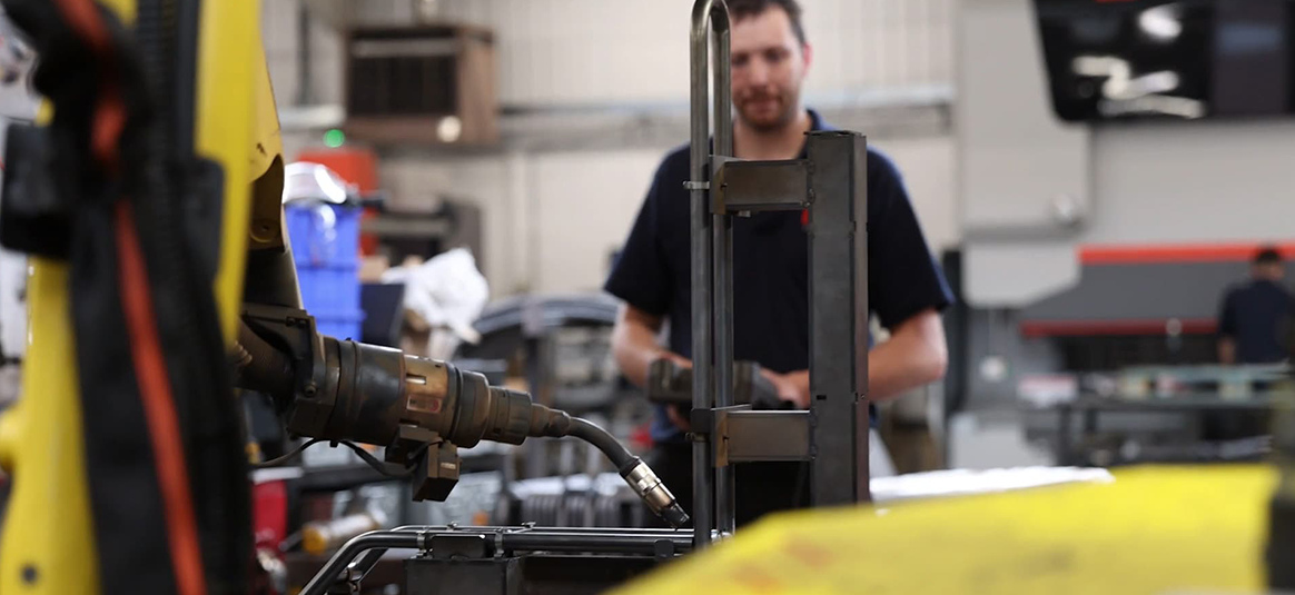 Photo of a person overseeing an automated welding robot
