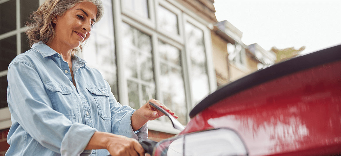 A woman charging a red electric car