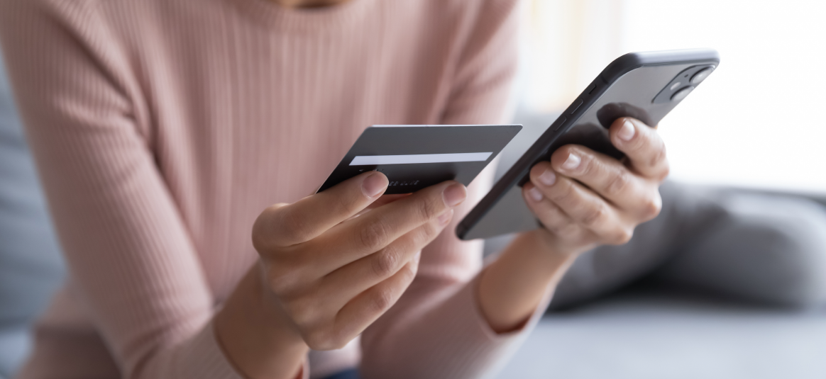 A person holding a payment card and a phone