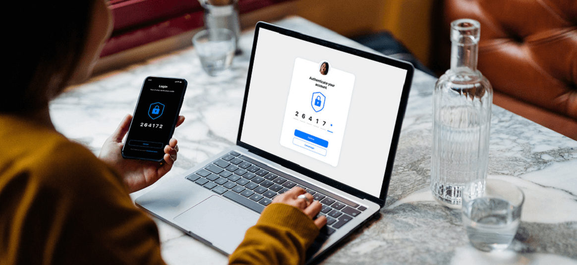 A person confirming their one time passcode on a phone to verify access to their laptop