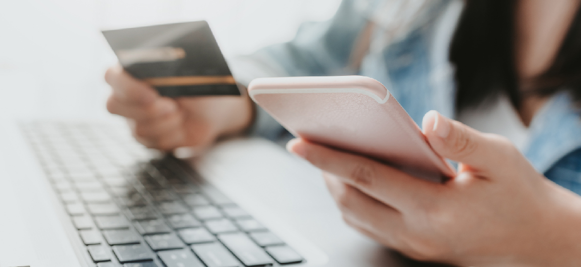 Photo of a person with a laptop and a mobile phone making a card payment.