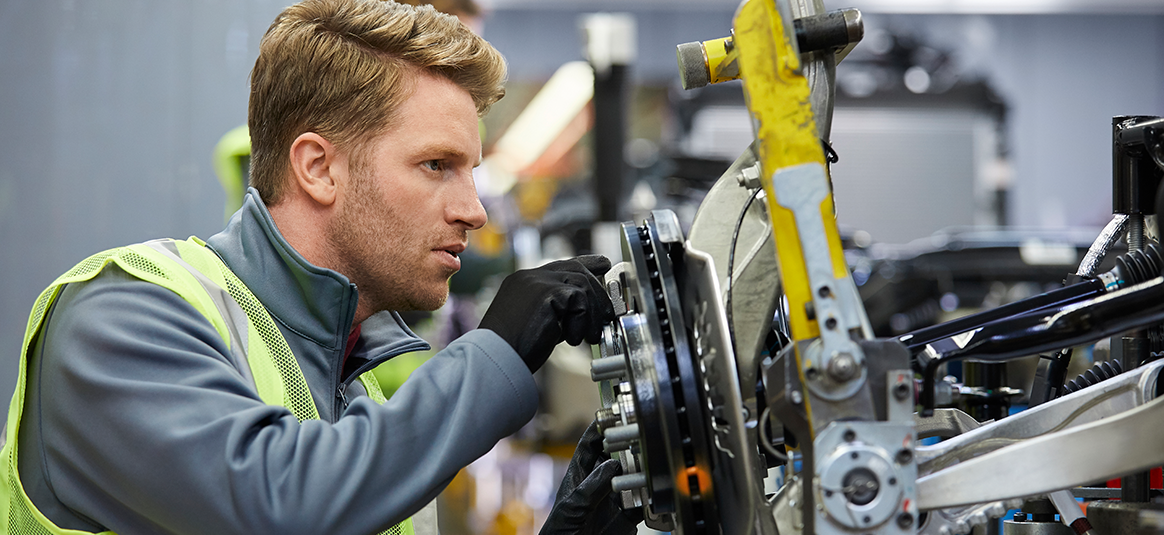 Photo of a person working on a disc brake system in a high visibility vest.